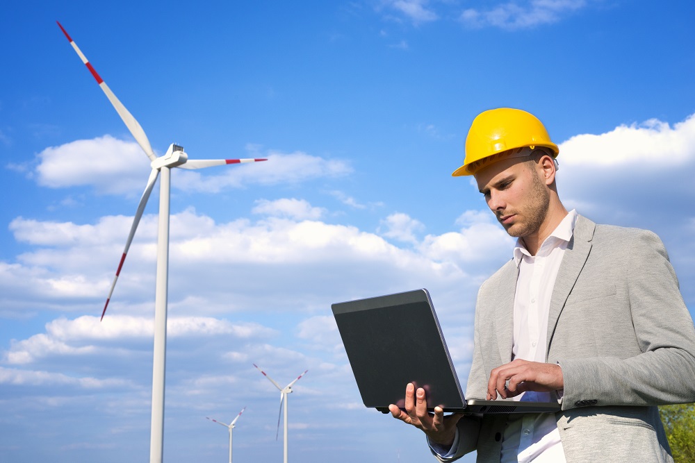 Engineer working on his laptop in front of wind generators